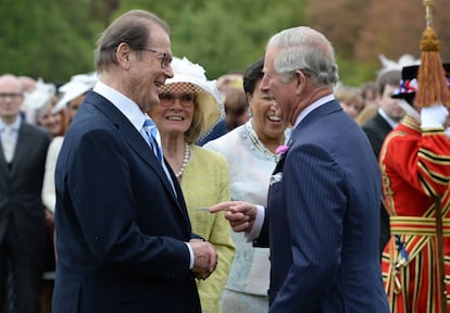 O Príncipe Charles conversa com o ator Roger Moore durante uma festa no jardim do Palácio de Buckingham, Londres, em 17 de maio de 2016.