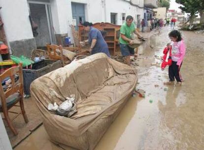 Vecinos de El Verger (Alicante) sacan los muebles de su casa, inundada por la crecida del río Girona.