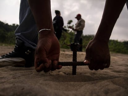 Un hombre entierra una varilla para buscar cuerpos en Colinas de Santa Fe, Veracruz. 