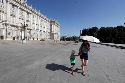 Una mujer y una niña se protegen del sol junto al Palacio Real de Madrid.