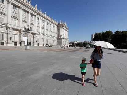 Una mujer y una niña se protegen del sol junto al Palacio Real de Madrid.