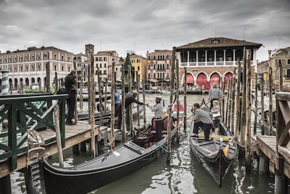 Gondoleros en el Gran Canal, con el edificio neog&oacute;tico del mercado de pescados de Rialto al fondo.