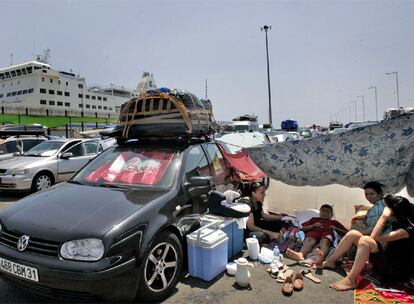 Una familia se protegía con un sombrajo junto a su coche, ayer, en el puerto de Alicante.