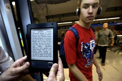 Un usuario sostiene un libro electrónico en el metro de Barcelona.