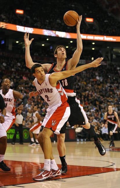 El jugador de los Portland Trail Blazers Víctor Claver alcanza un pase ante la marca de Landry Fields, de los Toronto Raptors