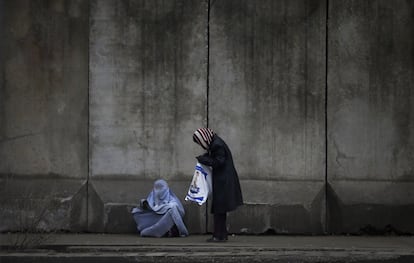 Una mujer pide dinero en el exterior de la comisaría de policía en la ciudad de Kabul (Afganistán).