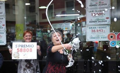 Las loteras María Jesus (d) y Begoña celebran el reparto del quinto premio de la lotería de Navidad, que le ha tocado al número 58808, en un punto de venta de la calle Castaños de la capital vizcaína.