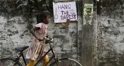 Una niña pasa junto a un cartel en el que se lee "Colgad al violador" en el muro donde una monja fue agredida sexualmente en Ranaghat (India).