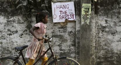 Una niña pasa junto a un cartel en el que se lee "Colgad al violador" en el muro donde una monja fue agredida sexualmente en Ranaghat (India).