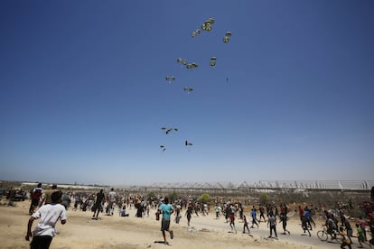 Gazatíes acuden corriendo a recoger la ayuda humanitaria lanzada en paracaídas el 30 de mayo de 2024 en Jan Yunis.