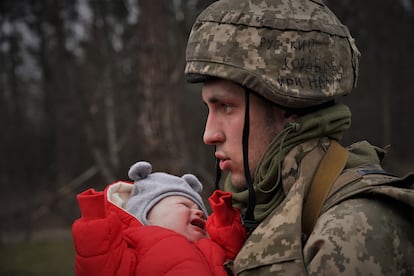 Un joven militar ucranio entrega un bebé a su madre tras cruzar los cascotes del puente de Irpin, cerca de
Kiev (Ucrania), el 5 de marzo de 2022.