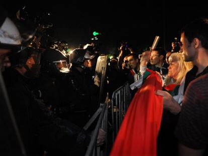 Un grupo de manifestantes trata de derribar una valla frente a la policía esta noche en Sofía.