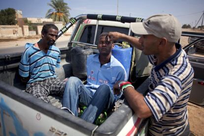 Un rebelde observa a dos supuestos gadafistas apresados en Sirte, el viernes.