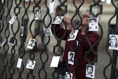 Una mujer coloca fotos de personas desaparecidas durante la represión en Guatemala.