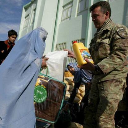 Un soldado de la ISAF reparte mantas y alimentos en Herat.