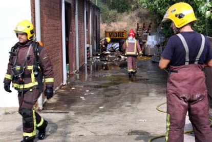 Los bomberos apagan los últimos rescoldos en la fábrica.