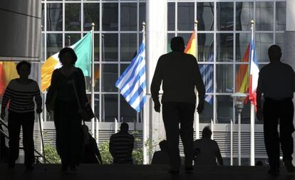 Viandantes en las escaleras del Parlamento Europeo en Bruselas donde ondean las banderas de la UE.