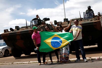 Seguidores de Bolsonaro posam diante de veículos do Exército, que participam da escola da posse. 