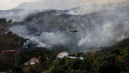 Un helicóptero vuela antes de arrojar agua sobre el incendio que se acerca a las casas en Benahavis.