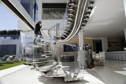 El desarrollador Bruce Makowsky sube una escalera de acero artesanal junto a una gran escultura de una cámara Leica, en el interior de la mansión.