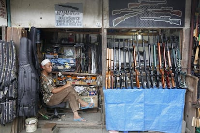 Un vendedor de escopetas de aire comprimido espera clientes en su comercio en una calle de Bogor (Indonesia).