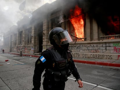 Un policía camina junto al Congreso en llamas en Ciudad de Guatemala, este sábado.
