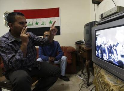 Hombres iraquíes contamplan el desarrollo del debate previo a la votación del acuerdo que pacta con EE UU la salida de sus soldados. Un grupo de diputados afines al clérigo chií Mukhtada al Sader, contrario a trato alguno con los norteamericanos, aparece en la imagen con una pancarta que reza "no al acuerdo"