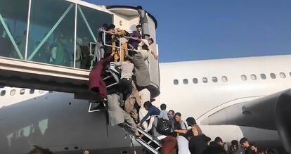 Afegãos tentam acessar um avião no aeroporto de Cabul na segunda-feira.