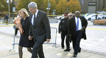 El primer ministro Stephen Harper acompañado de su esposa, Laureen, caminan cerca del monumento a los caídos, cuando un hombre se ha saltado el cordón policial y un miembro de su escolta ha sacado un arma para defenderlos, el 23 de octubre de 2014.