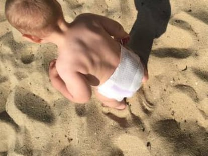 Un beb&eacute; juega en una playa gallega.