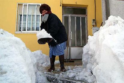 Una mujer despeja la puerta de su casa tras la intensa nevada caida en la localidad de Cebreiro, en Lugo.