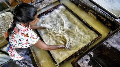 Una de las trabajadoras esparce la pasta de papel en la superficie de la pantalla enmarcada.