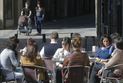 Un grupo de mujeres departe en una terraza de una calle del centro de la localidad vizcaina de Elorrio. Al fondo, una pareja pasea con un cochecito de bebé.