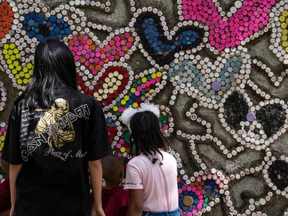 Unos niños pegan tapones de botellas de plástico en el llamado Muro del Amor, en el parque de Los Caobos, en Caracas, Venezuela, el 23 de diciembre de 2022. Esta es una iniciativa de la ONG Oko Spire para reciclar los tapones y evitar que contaminen el medio ambiente.