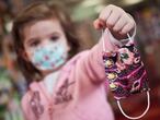 Una niña muestra una mascarilla infantil mientras sale a la calle en el primer día de relajamiento del confinamiento. 