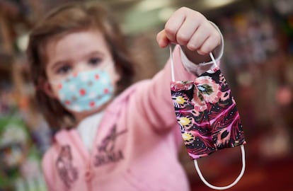 Una niña muestra una mascarilla infantil mientras sale a la calle en el primer día de relajamiento del confinamiento.