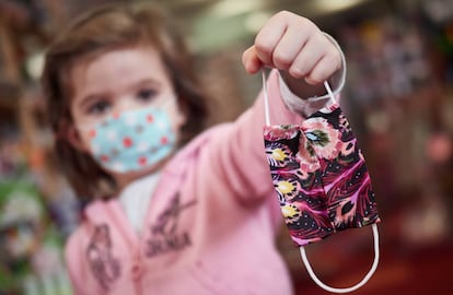 Una niña muestra una mascarilla infantil mientras sale a la calle en el primer día de relajamiento del confinamiento. 