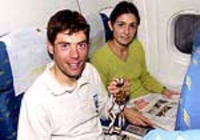 Óscar Freire, junto a su novia, Laura, muestra en el avión de regreso desde Lisboa su medalla de oro.