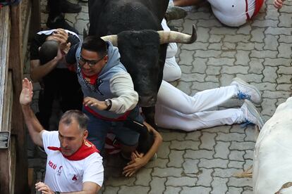 Varios mozos caen al suelo al paso de uno de los astados de la ganadería de Mira, en el tramo del callejón a la Plaza de Toros de Pamplona.