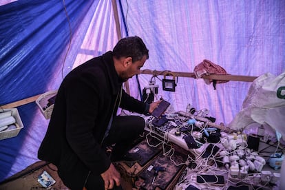 El gazatí Mahmoud Al-Benna carga teléfonos móviles gracias a un precario sistema de paneles solares, el 17 de enero de 2024 en Rafah.