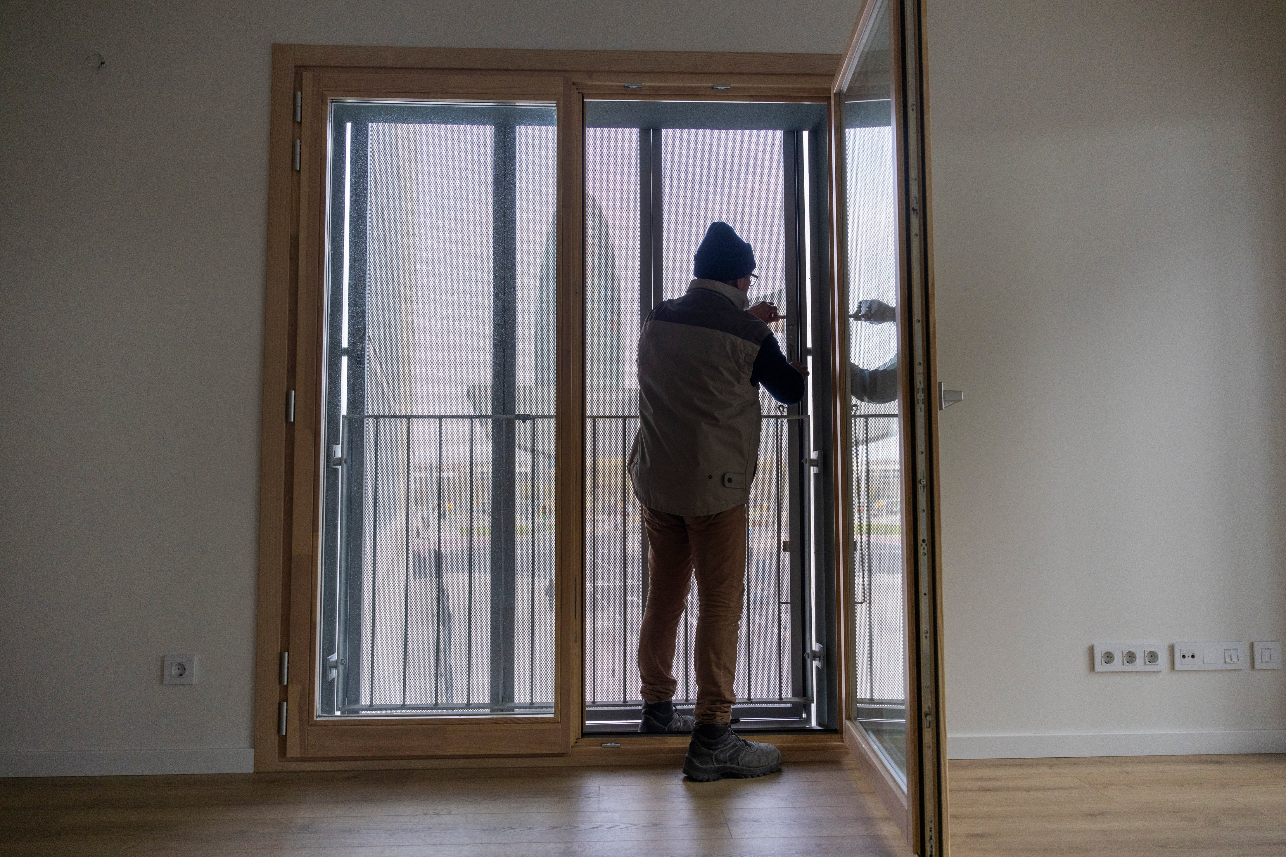 Un hombre repara el balcón de una vivienda de Barcelona.