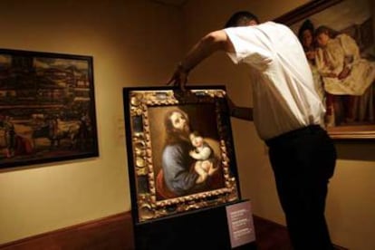 Un técnico coloca la pintura <i>San José con el Niño,</i> de Zurbarán.