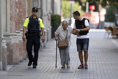 Efectivos policiales acompañando a una mujer mayor cerca del área en la que se ha producido el atentado terrorista en Las Ramblas de Barcelona.