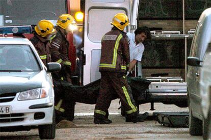 Bomberos y los Servicio Funerarios trasladan el cuerpo sin vida de uno de los cuatro muertos en el accidente.