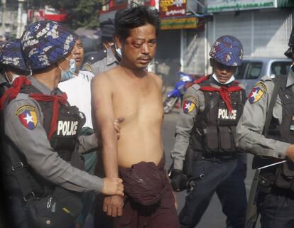 Un manifestante herido en un ojo es arrestado durante protestas en las calles de Yangon este viernes