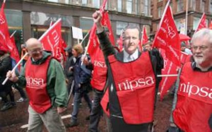 Un sindicalista de Irlanda del Norte (c) porta un recorte del primer ministro británico, David Cameron durante una manifestación ayer contra el G8 en la ciudad de Belfast, Irlanda del Norte.