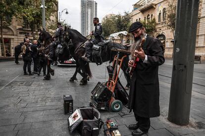 Un judío ultraortodoxo toca la guitarra en la calle Jaffa junto a un grupo de policías en Jerusalén, este martes.