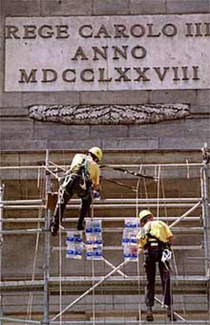 Dos operarios suben a la Puerta de Alcalá los primeros libros donados para Centroamérica y Colombia.