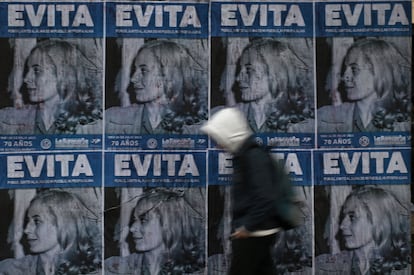 Un hombre camina junto a muro cubierto de afiches con un retrato de la ex primera dama argentina, en Buenos Aires, el 25 de julio de 2022, en vísperas del 70 aniversario de su muerte.