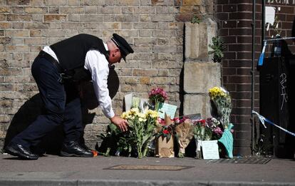 Un oficial de policía deposita unas flores cerca de la escena, en Finsbury Park.